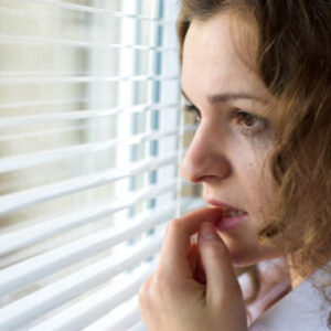 Headshot of Anxious Young Woman at Window